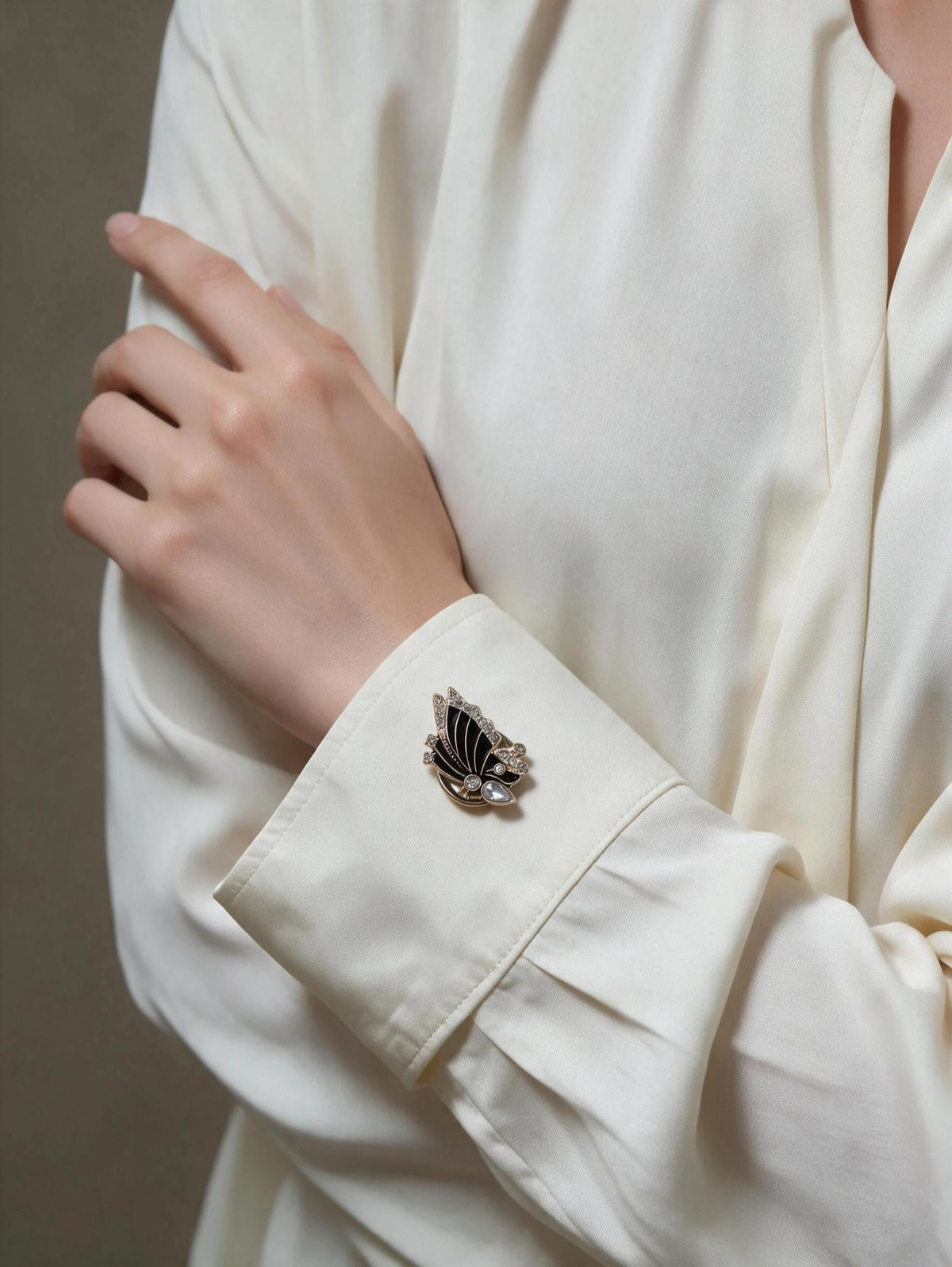 Black butterfly button cover worn on the cuff of an ivory shirt