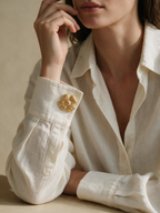 Gold ribbed flower cuff button cover worn on a cream shirt cuff